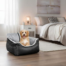 DreammyDoggie black and grey dog car booster seat with a small puppy sitting inside on a wooden floor in a bedroom