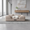 DreammyDoggie khaki sofa dog bed with a small white dog sleeping on it, placed on a grey rug in a modern living room.