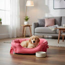 DreammyDoggie pink plush princess dog bed with a bow detail, featuring a small puppy resting inside on a wooden floor.