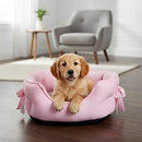 DreammyDoggie pink plush anti-anxiety princess dog bed with bow details, featuring a puppy resting inside.