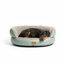 DreammyDoggie round plush dog sofa bed in sage green with a Doberman puppy resting inside on a white background